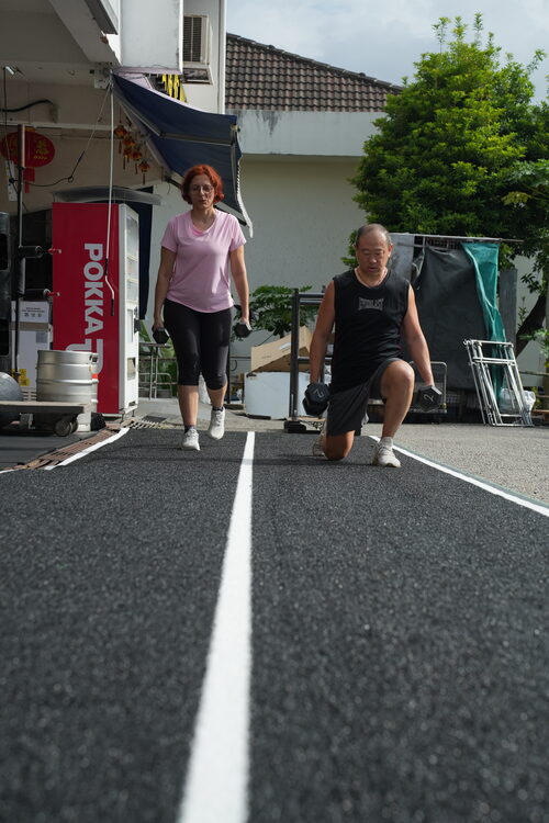 An older member and a younger member training side by side outdoors — all ages welcome at SwoleFit Garage